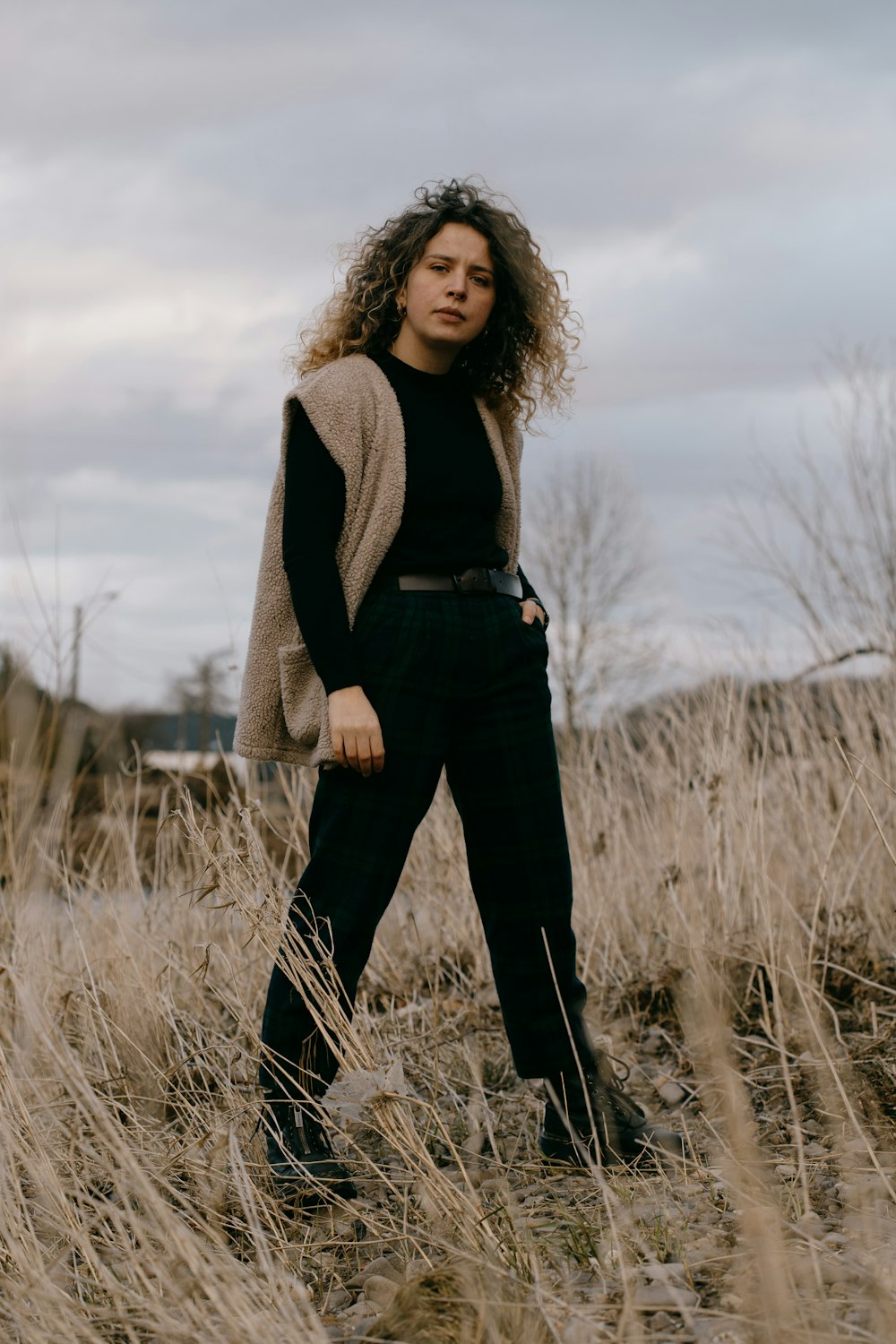 woman in gray cardigan standing on grass field during daytime