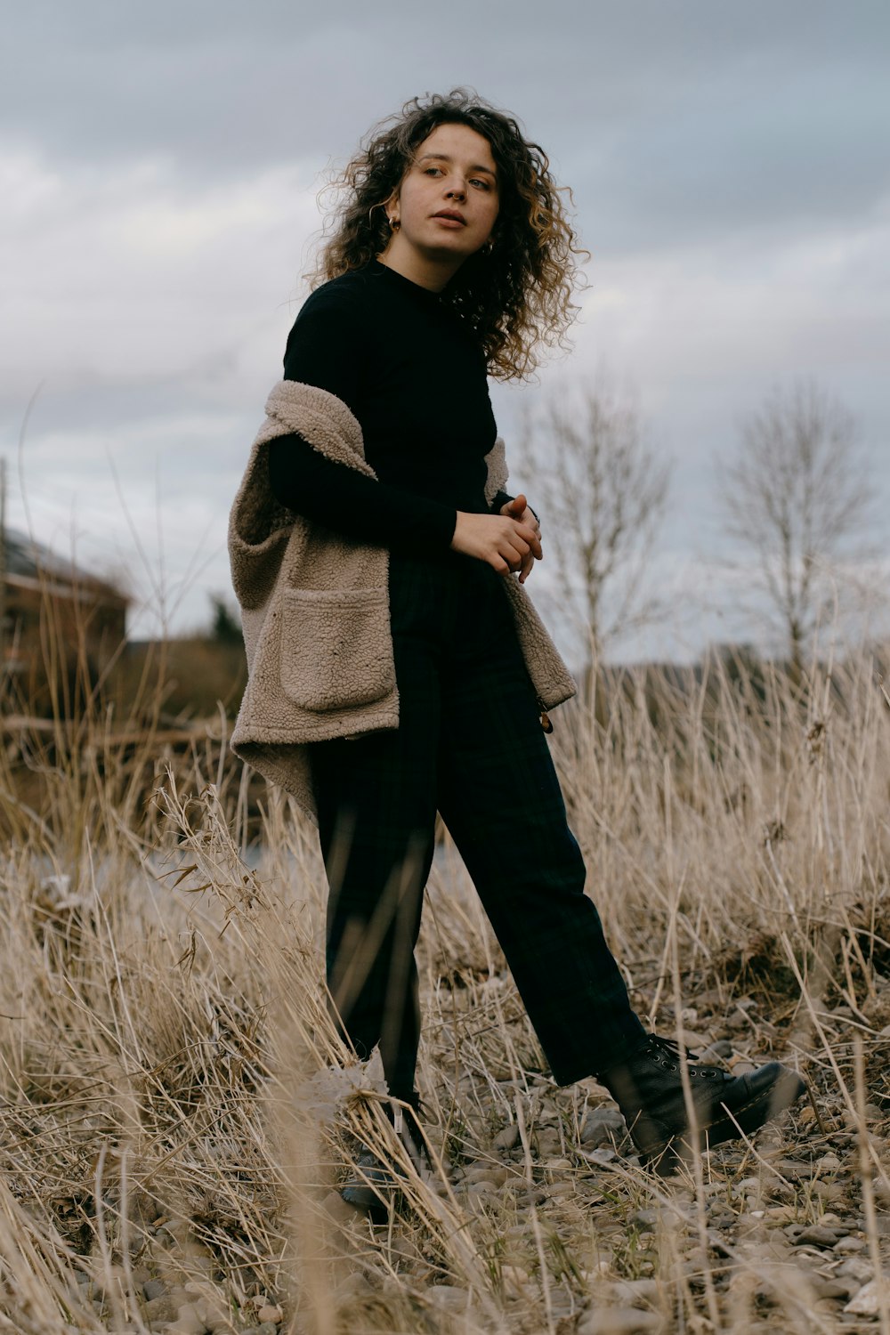 woman in black long sleeve shirt and gray scarf standing on grass field during daytime