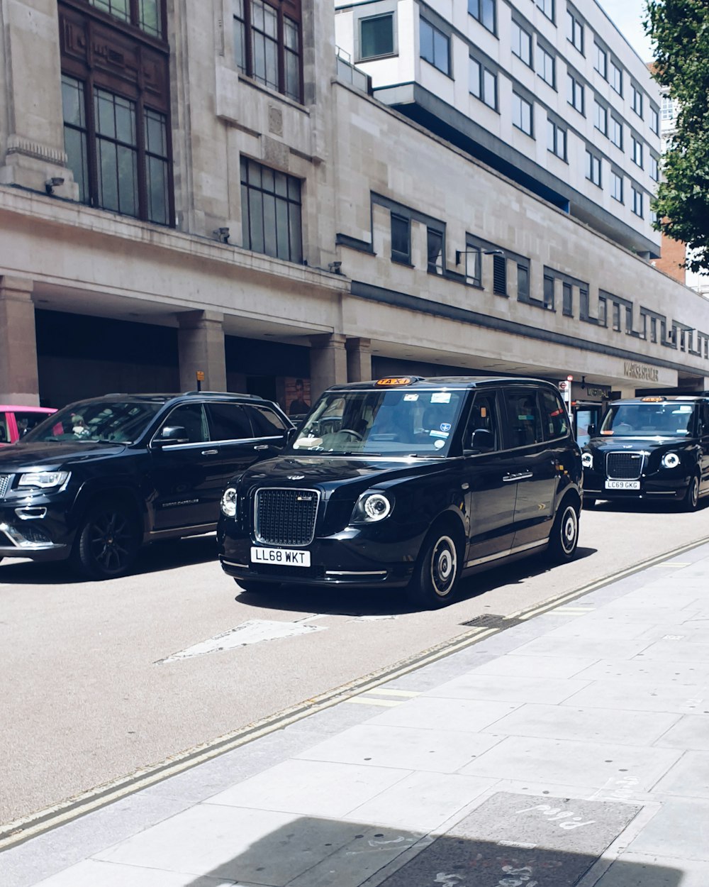 black mercedes benz g class parked on sidewalk during daytime