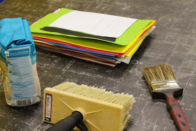 Stack of assorted sanding papers and rolls of masking tape used for automotive detailing.