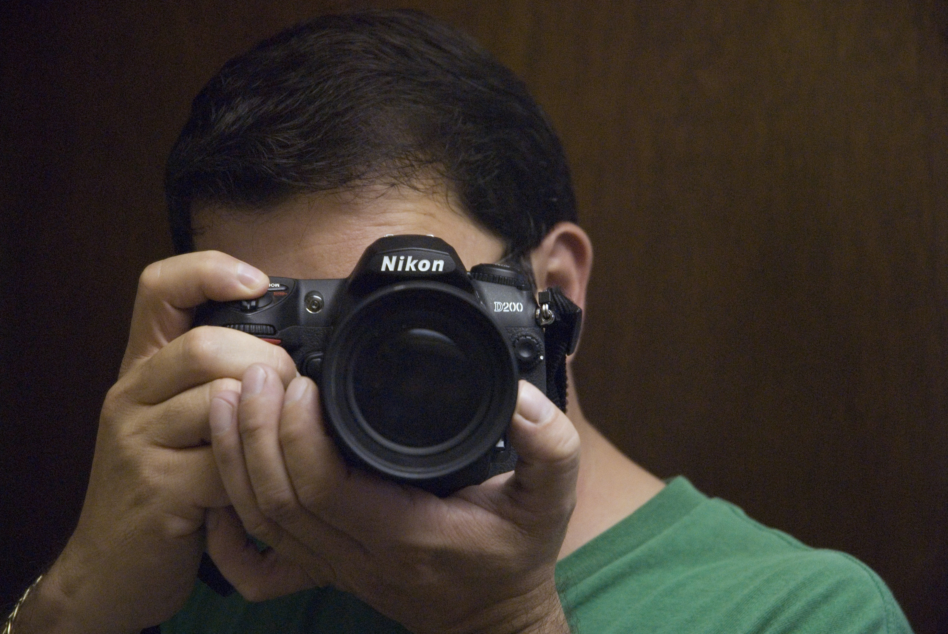 man in green shirt holding black nikon dslr camera