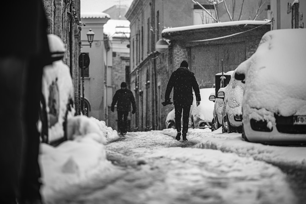 man in black jacket walking on snow covered road during daytime