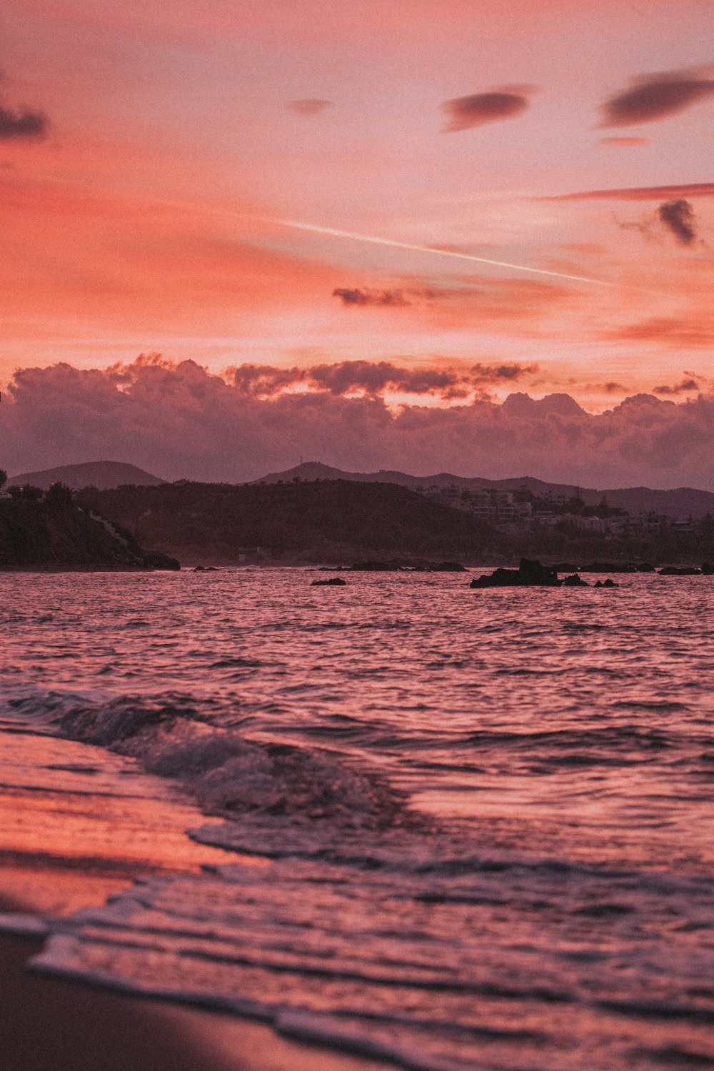 body of water near mountain during sunset