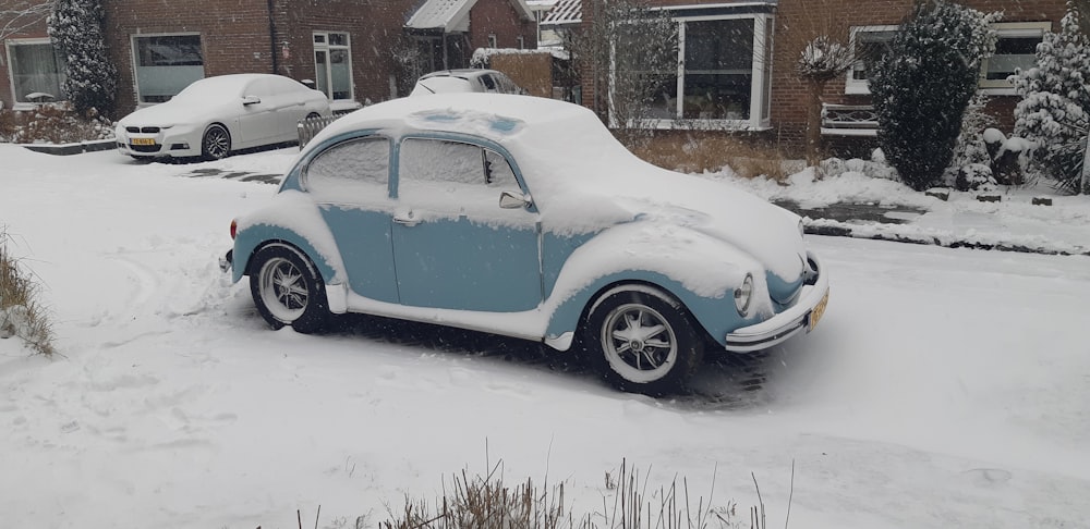 blue volkswagen beetle parked on snow covered ground during daytime