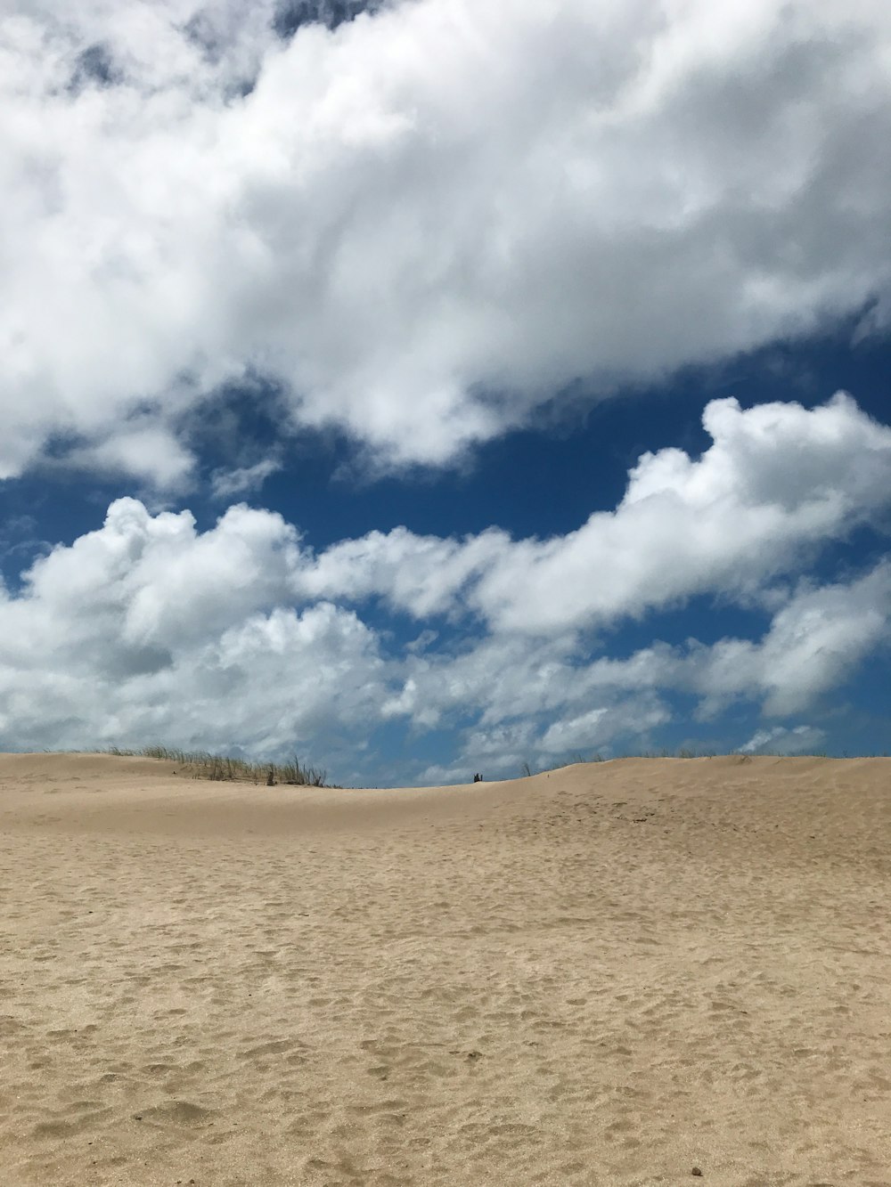 昼間の青い空と白い雲の下の茶色の砂