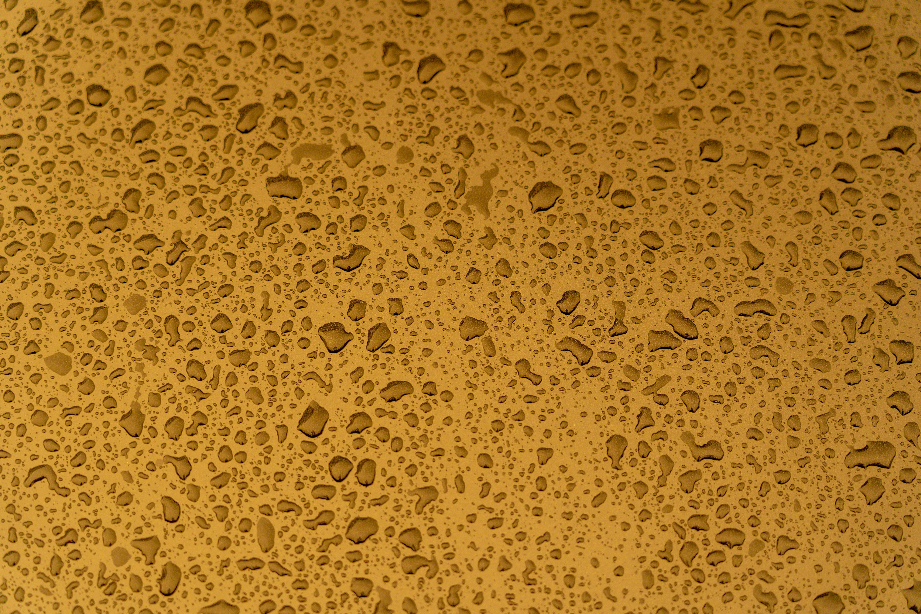 Raindrops on a yellow metal surface