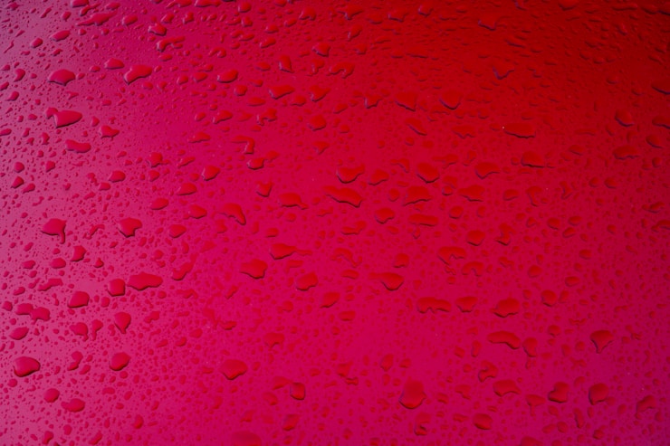 Raindrops on a red metal surface.