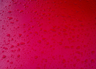 Raindrops on a red metal surface.