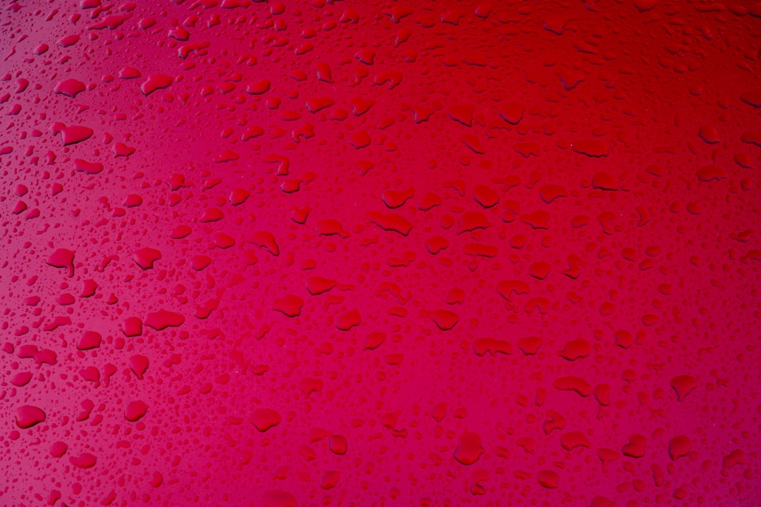 pink and white abstract painting, Raindrops on a red metal surface.
