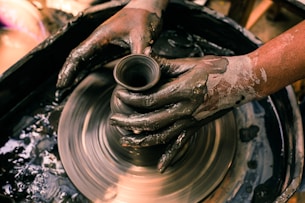 person making clay pot with water