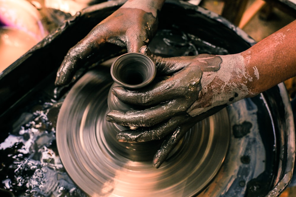 person making clay pot with water