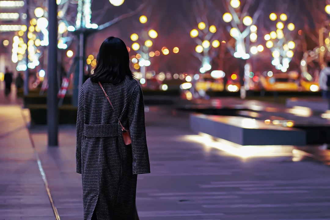 woman in black and white polka dot robe standing on street during night time
