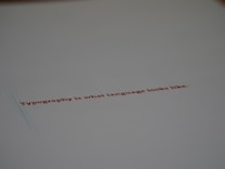 A minimalistic design featuring a piece of paper with the text 'Typography is what language looks like.' written in red ink. The focus on the text gives a stylish and modern feel with ample white space around it.