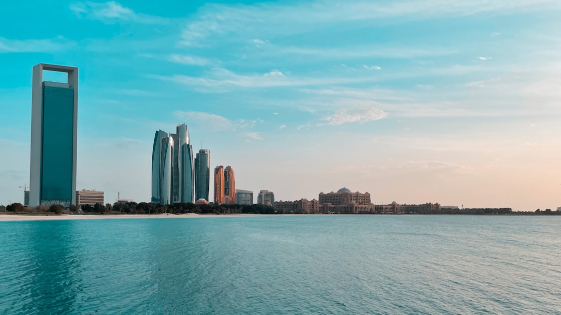 The Abu Dhabi skyline reflects in Gulf water along the Corniche waterfront.