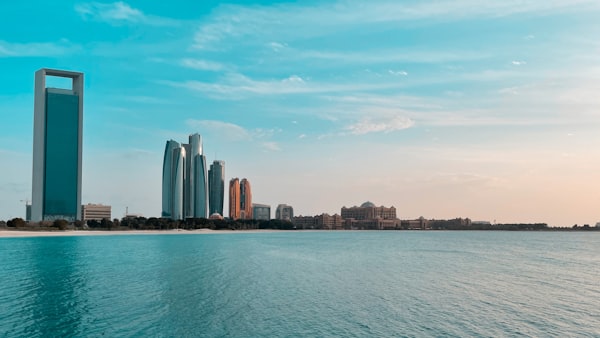 The Abu Dhabi skyline reflects in Gulf water along the Corniche waterfront.