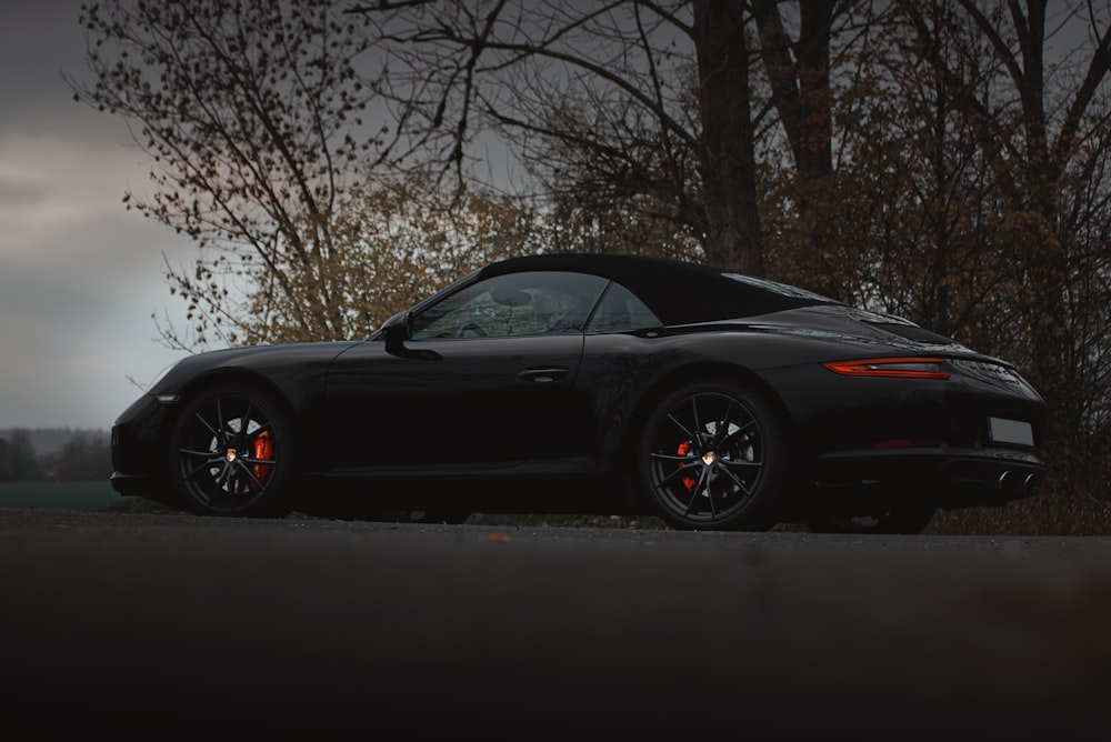 black porsche 911 parked near bare trees during daytime