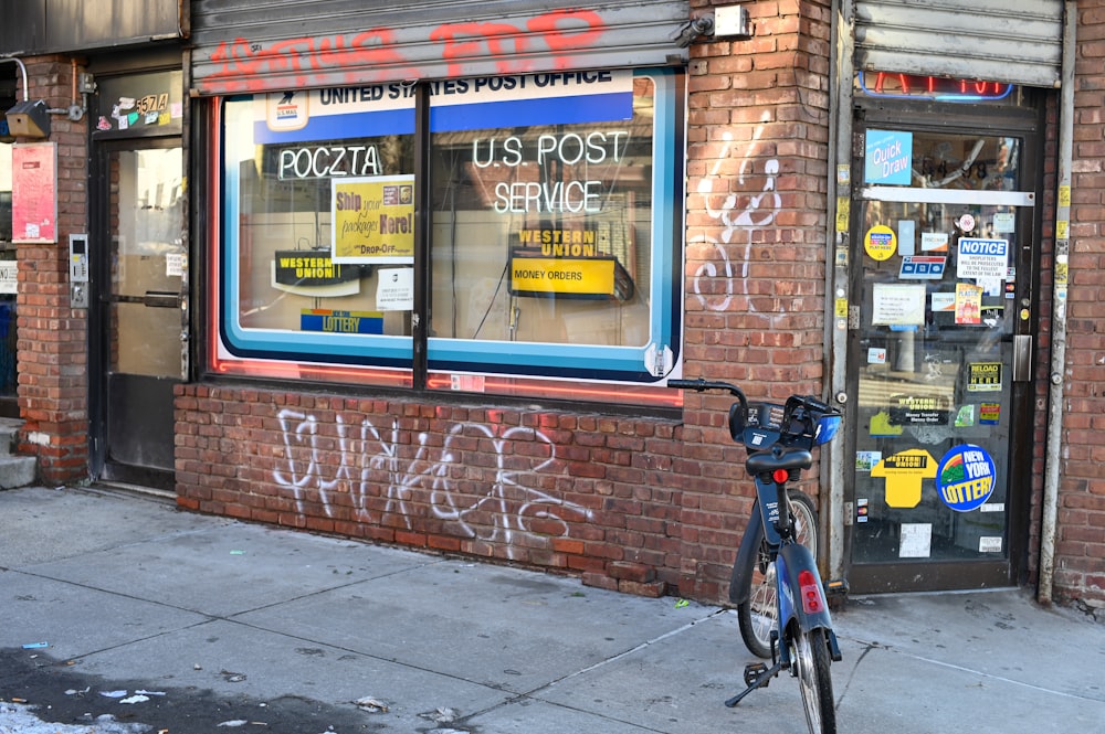 black bicycle parked beside brown brick wall