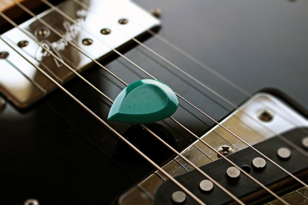 green guitar pick on black guitar