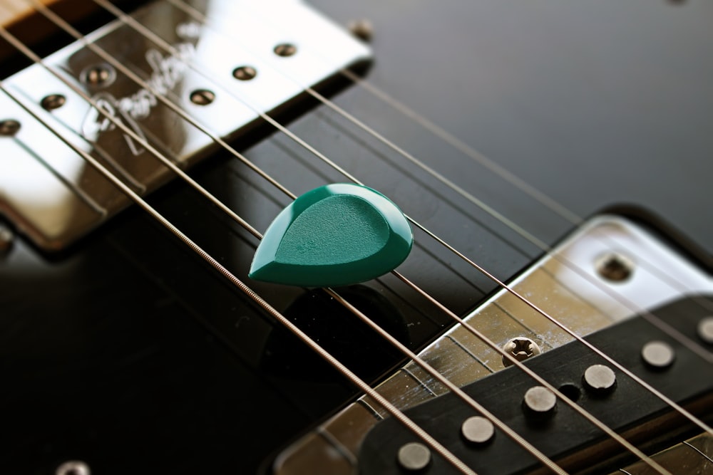 green guitar pick on black guitar