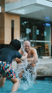 A cheerful toddler splashing gently in a shallow pool with a friendly instructor nearby.
