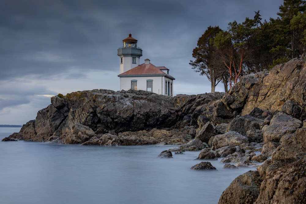 white and brown concrete house on brown rocky shore under cloudy sky during daytime