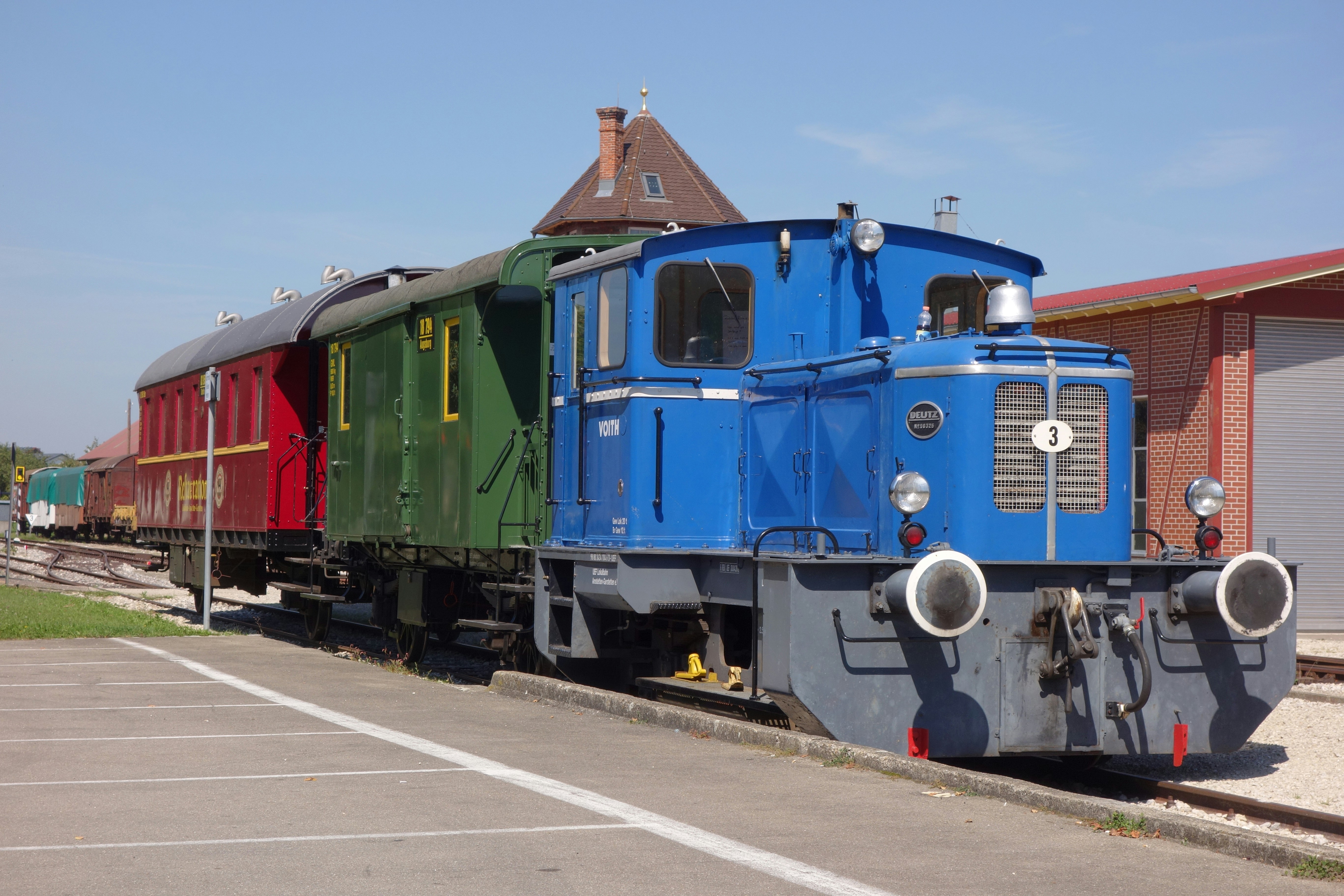 Train cars lined up in a depot, freshly painted with bright, clean colors.