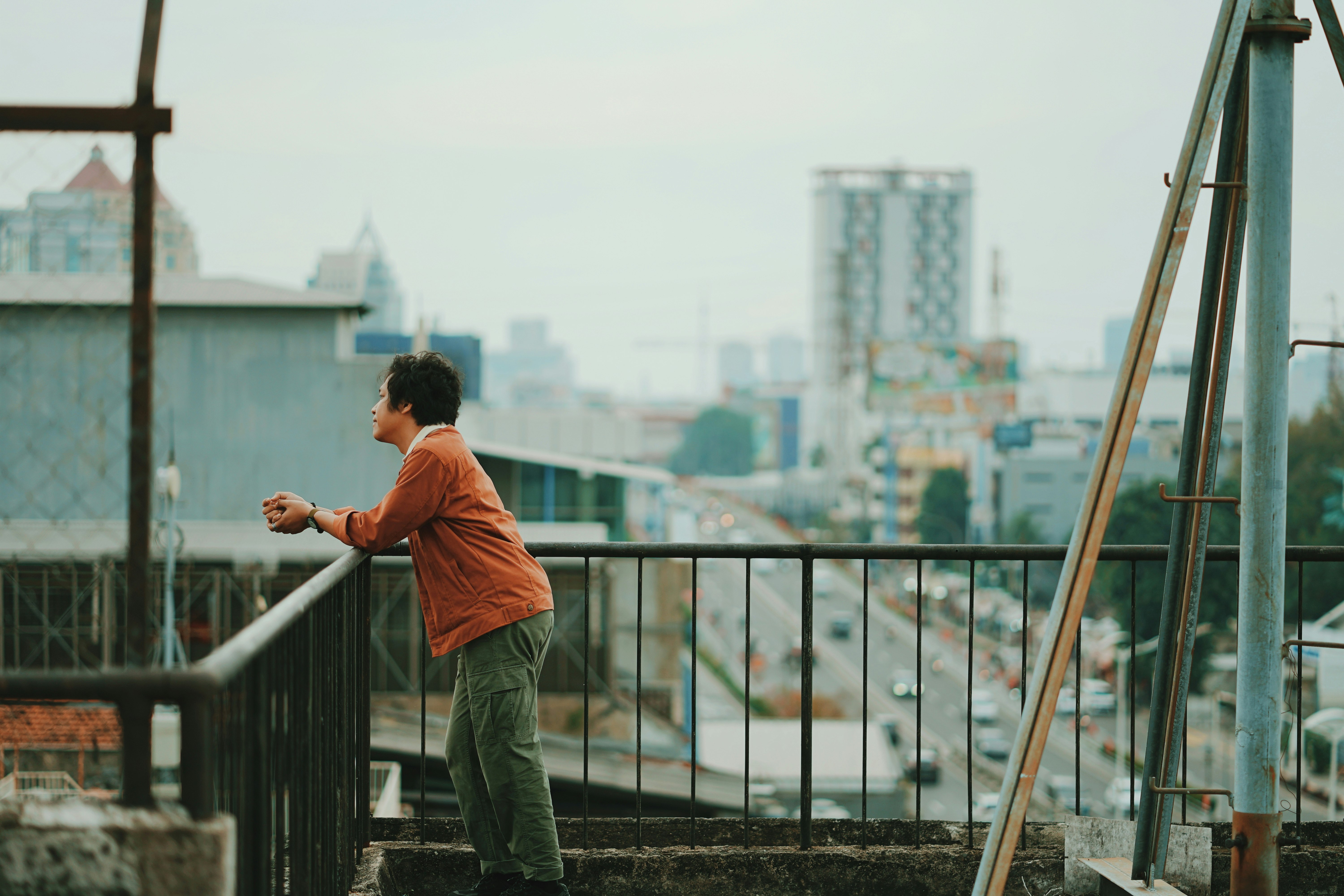 man in orange polo shirt and blue denim jeans standing on brown wooden dock during daytime