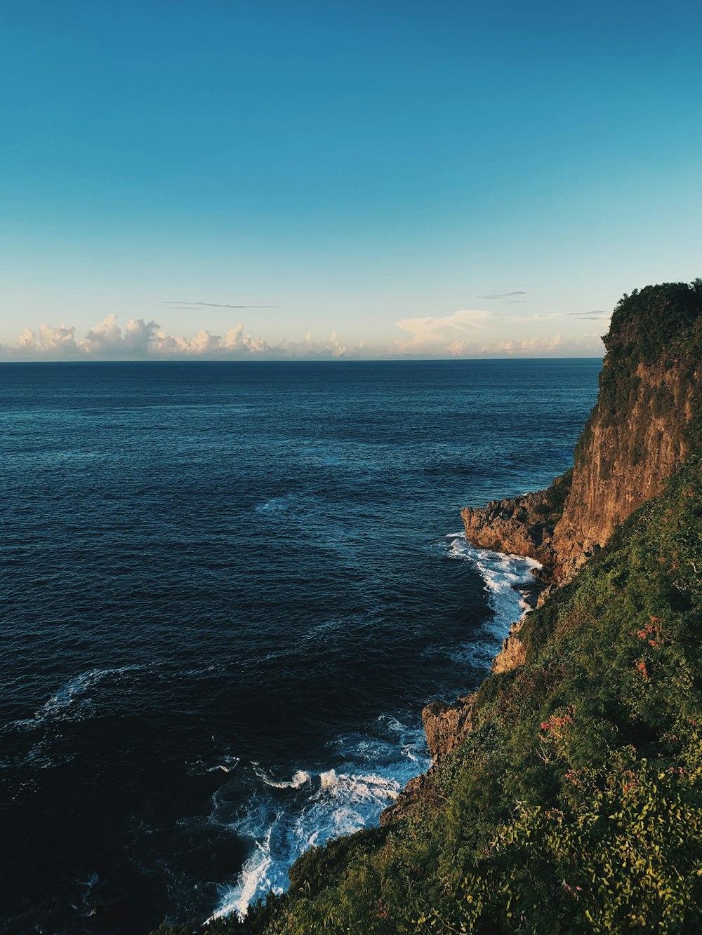 昼間の青空の下、青い海のそばの茶色の岩山