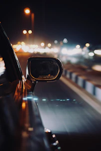 A dynamic shot of a supercar’s side mirror reflecting a blurred cityscape at night.
