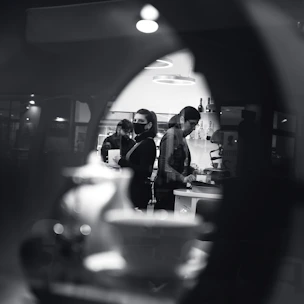 A sleek black and white photo of a modern manufacturing facility with workers inspecting high-quality kitchen appliances.