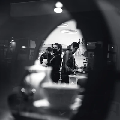 An old black-and-white photo of a Colombian family cooking together in a vintage kitchen.