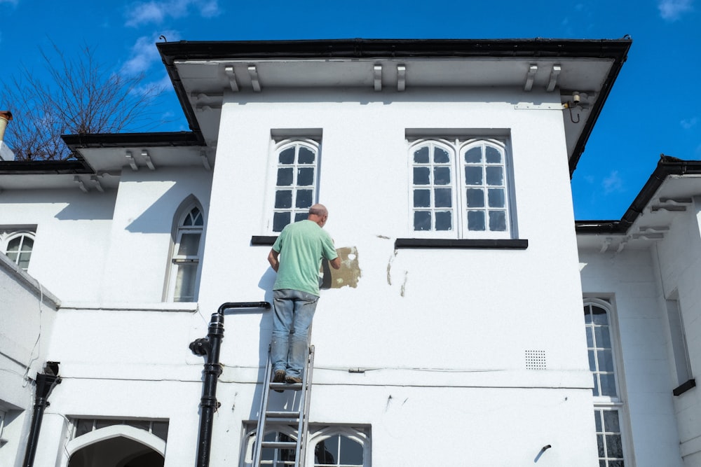 homme en chemise jaune et jean bleu debout sur un bâtiment en béton blanc pendant la journée