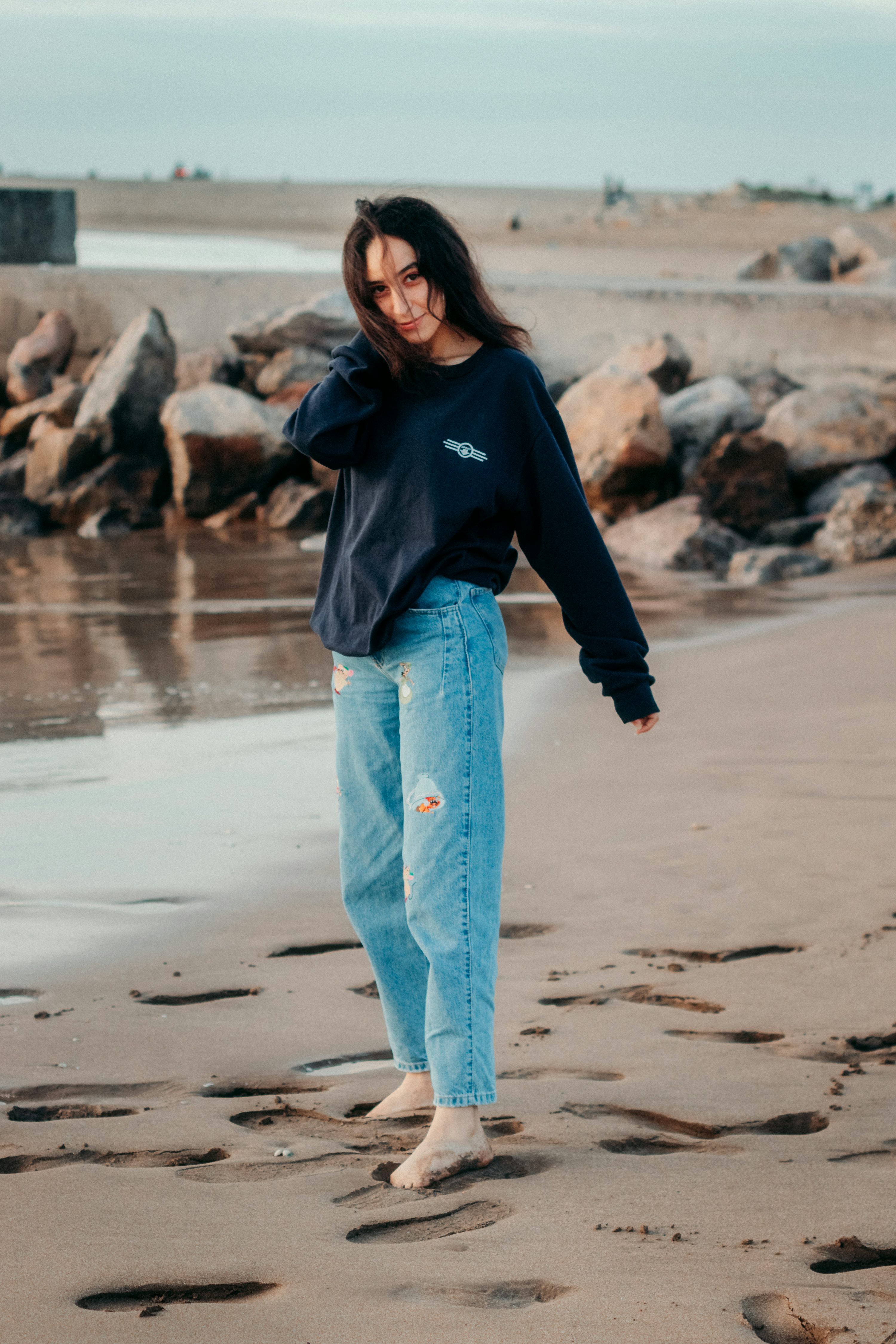 Mom Fit Jeans: Σε ποιες ταιριάζουν και πώς να τα φορέσετε 2 woman in black long sleeve shirt and blue denim jeans standing on beach shore during daytime