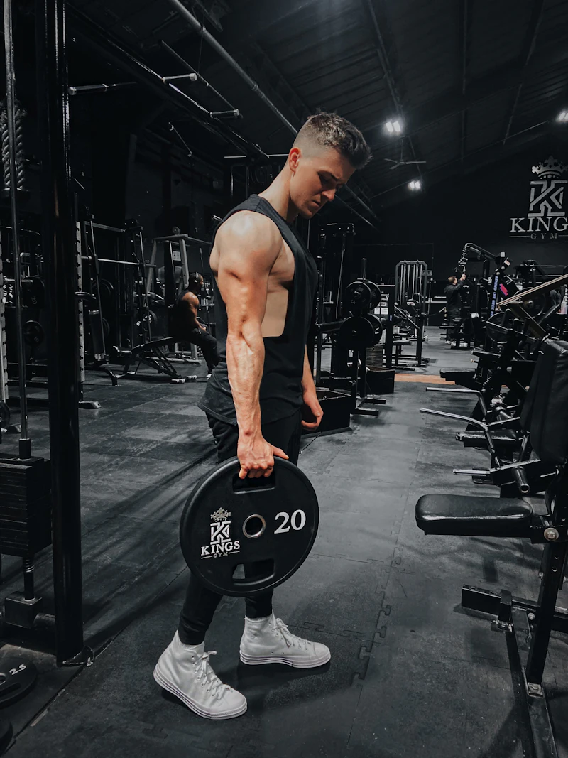 A lifter mid-set with a dumbbell in a dim gym