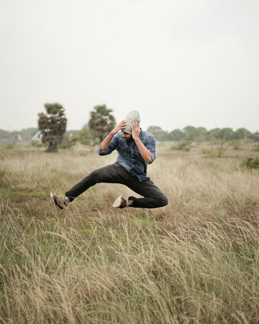 man in blue denim jeans and black shirt sitting on green grass field during daytime