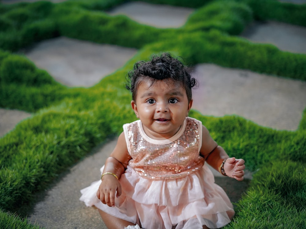 girl in white dress sitting on green grass field during daytime