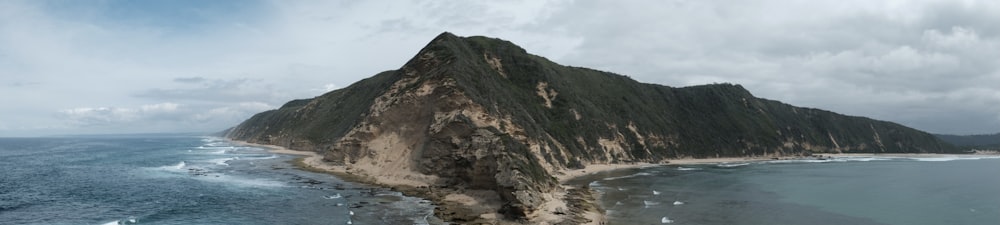 montanha marrom e verde ao lado do corpo de água durante o dia