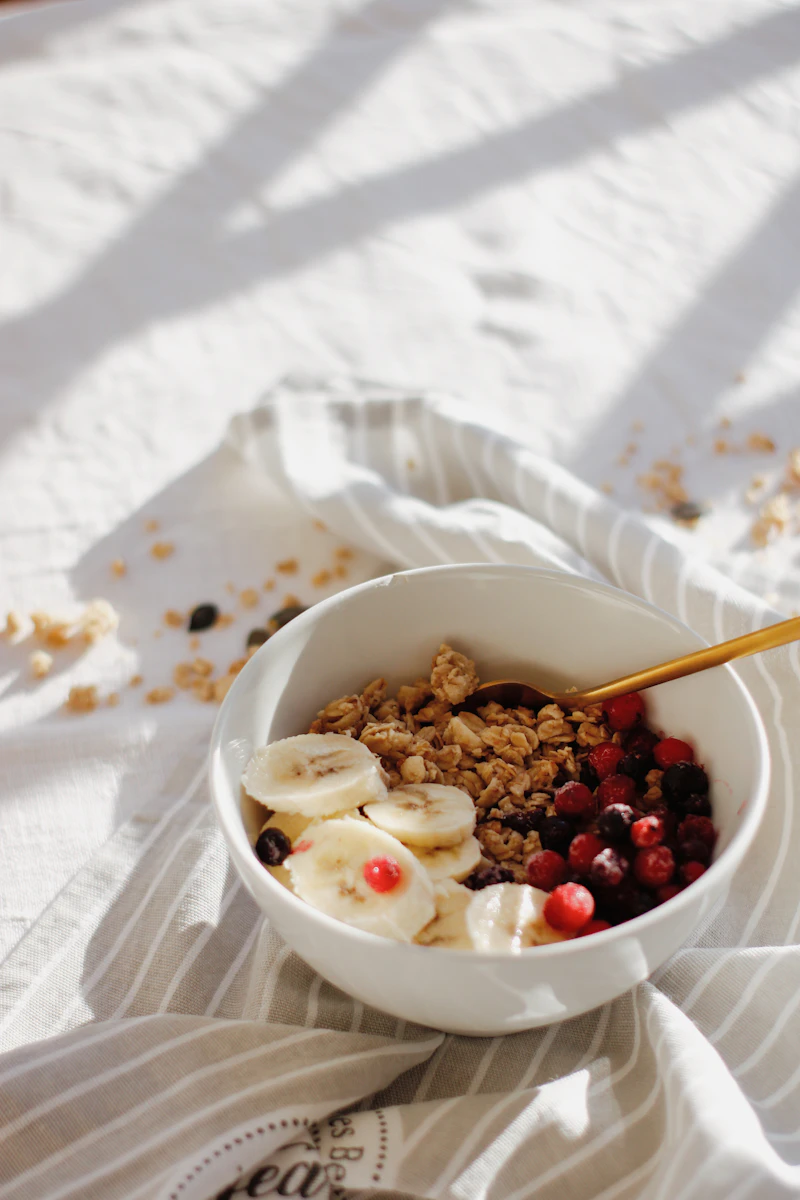 Bowl of granola with fruit on a linen cloth in soft natural light