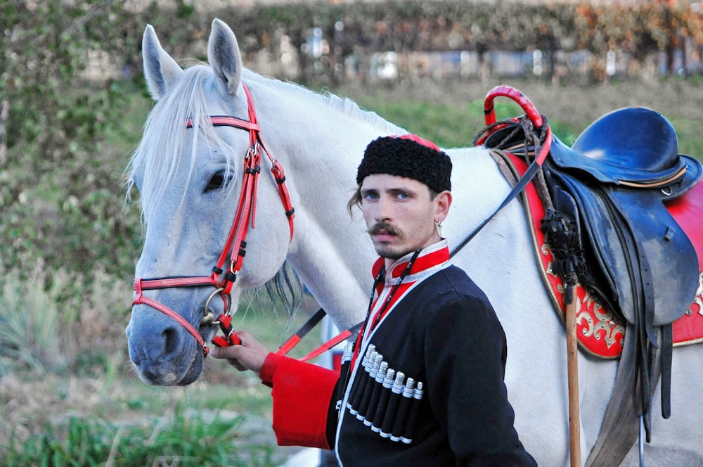 Hombre con chaqueta negra montando caballo blanco durante el día