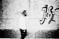 Dynamic street photo capturing movement with a model in a premium overshirt against a graffiti wall.