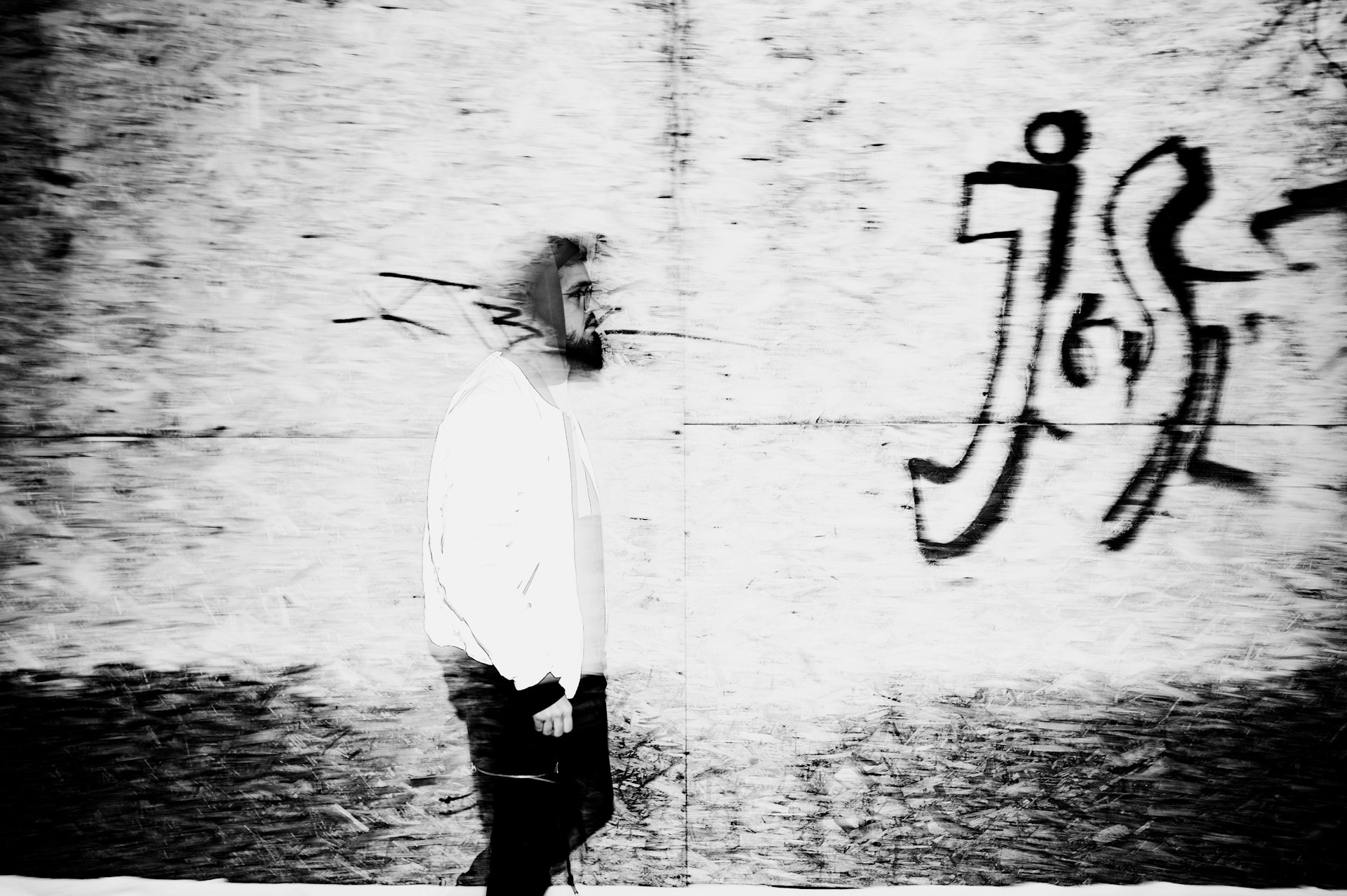 A candid street photography moment showing a passerby framed by urban graffiti and bustling city life.