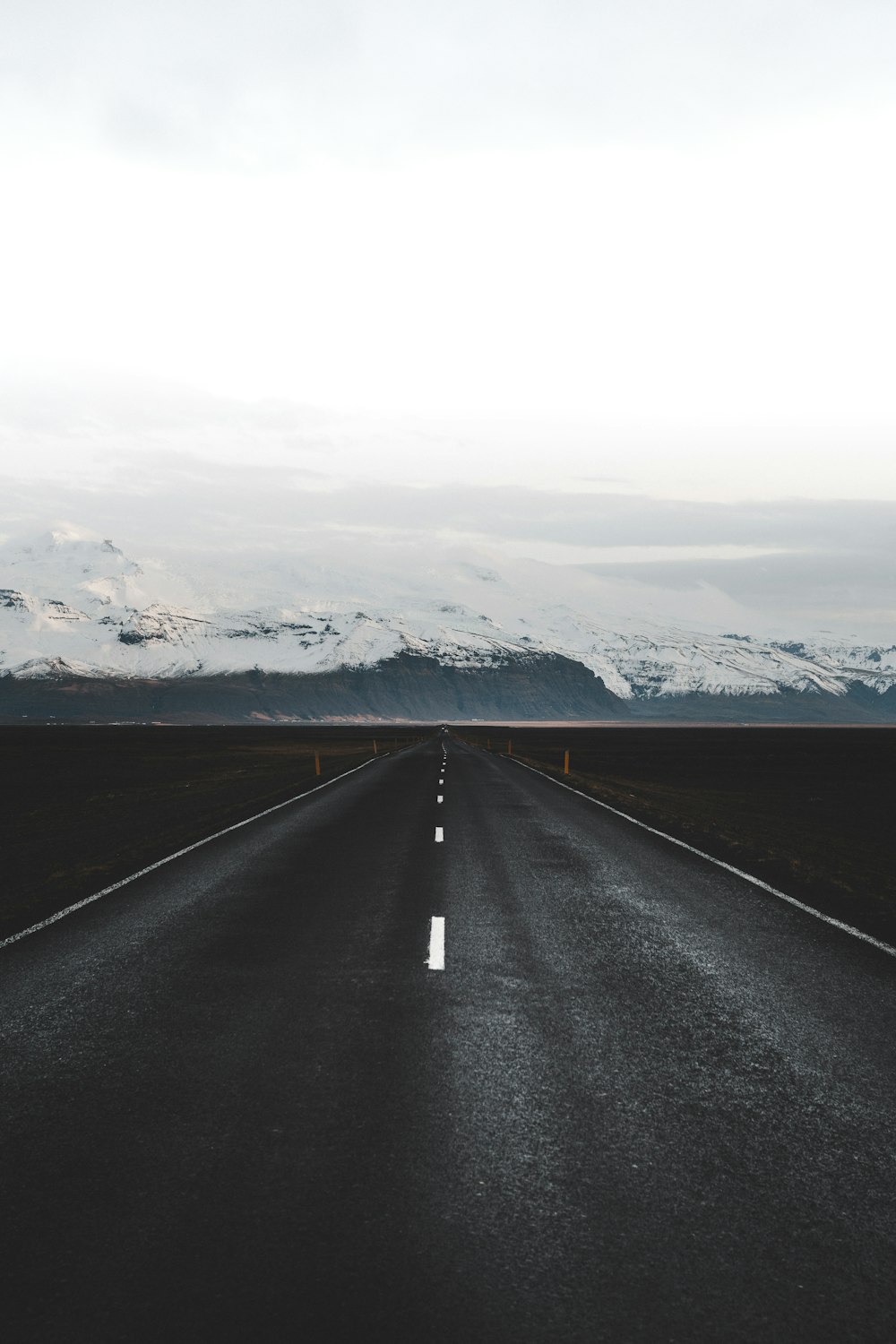 black asphalt road in between snow covered ground during daytime