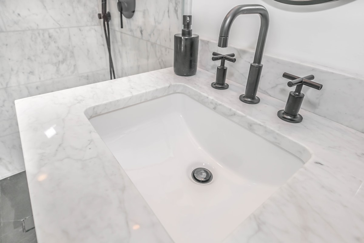 Marble vanity with a black cross-handle faucet