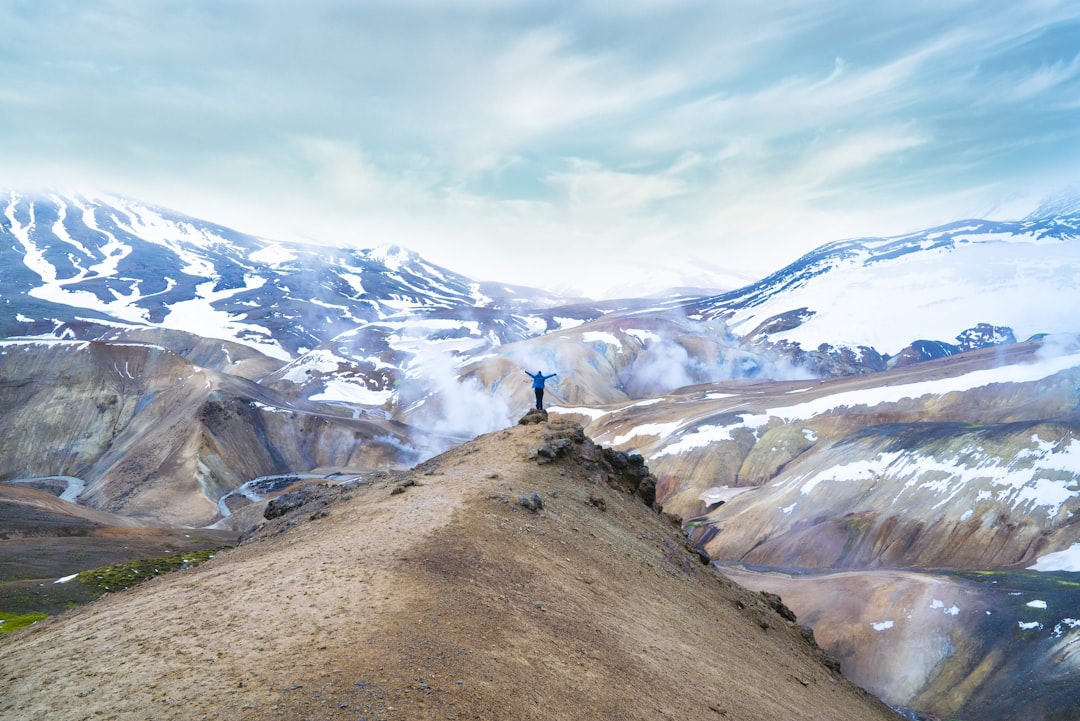 person in white shirt standing on brown rock mountain during daytime