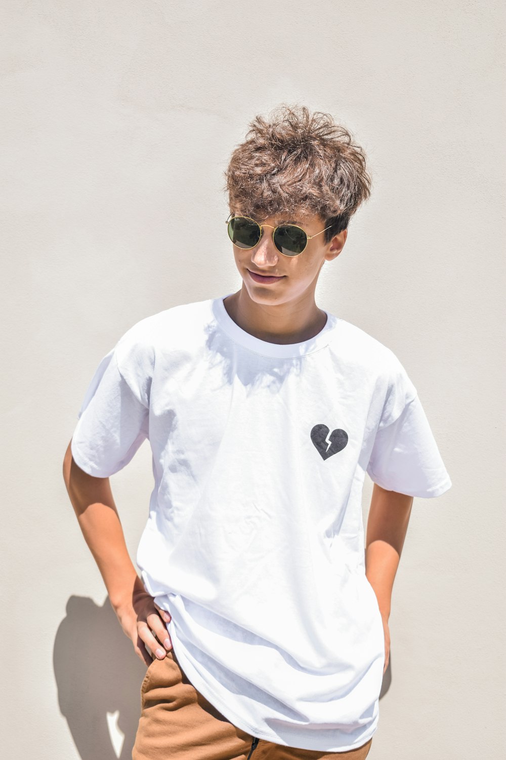 Garçon en T-shirt blanc à col rond portant des lunettes de soleil noires