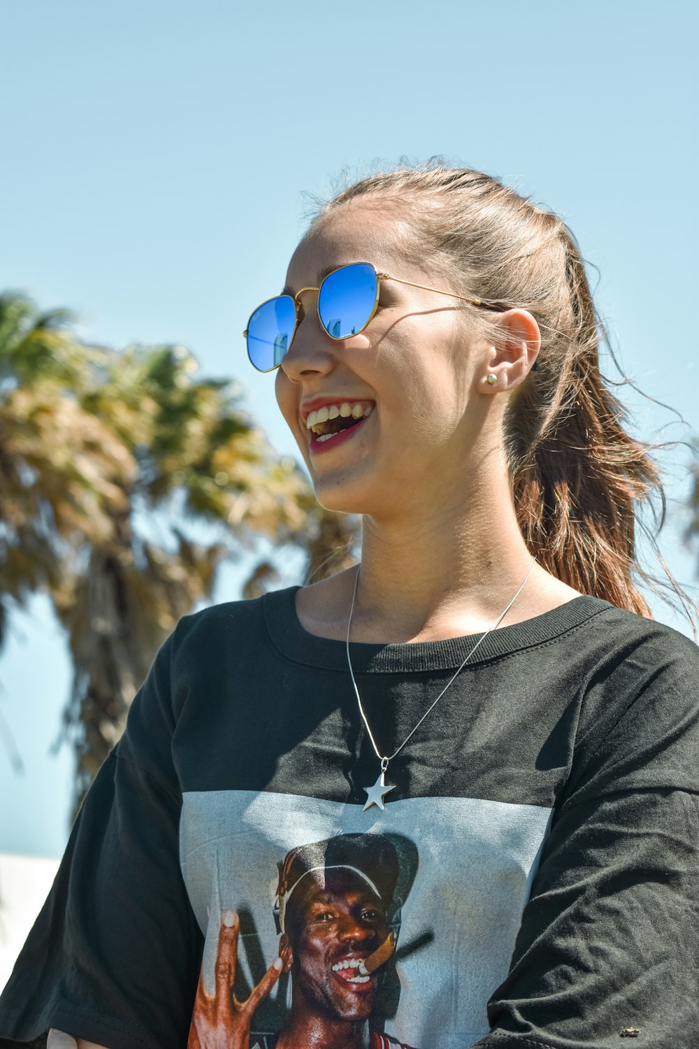 Mujer con camisa de cuello redondo en blanco y negro con gafas de sol azules