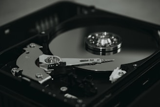 An open hard disk drive is displayed with its reflective magnetic disk and reading arm visible. The intricate mechanical components are showcased in a detailed manner, highlighting the precision of the hardware.