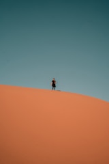 person in black jacket walking on desert during daytime