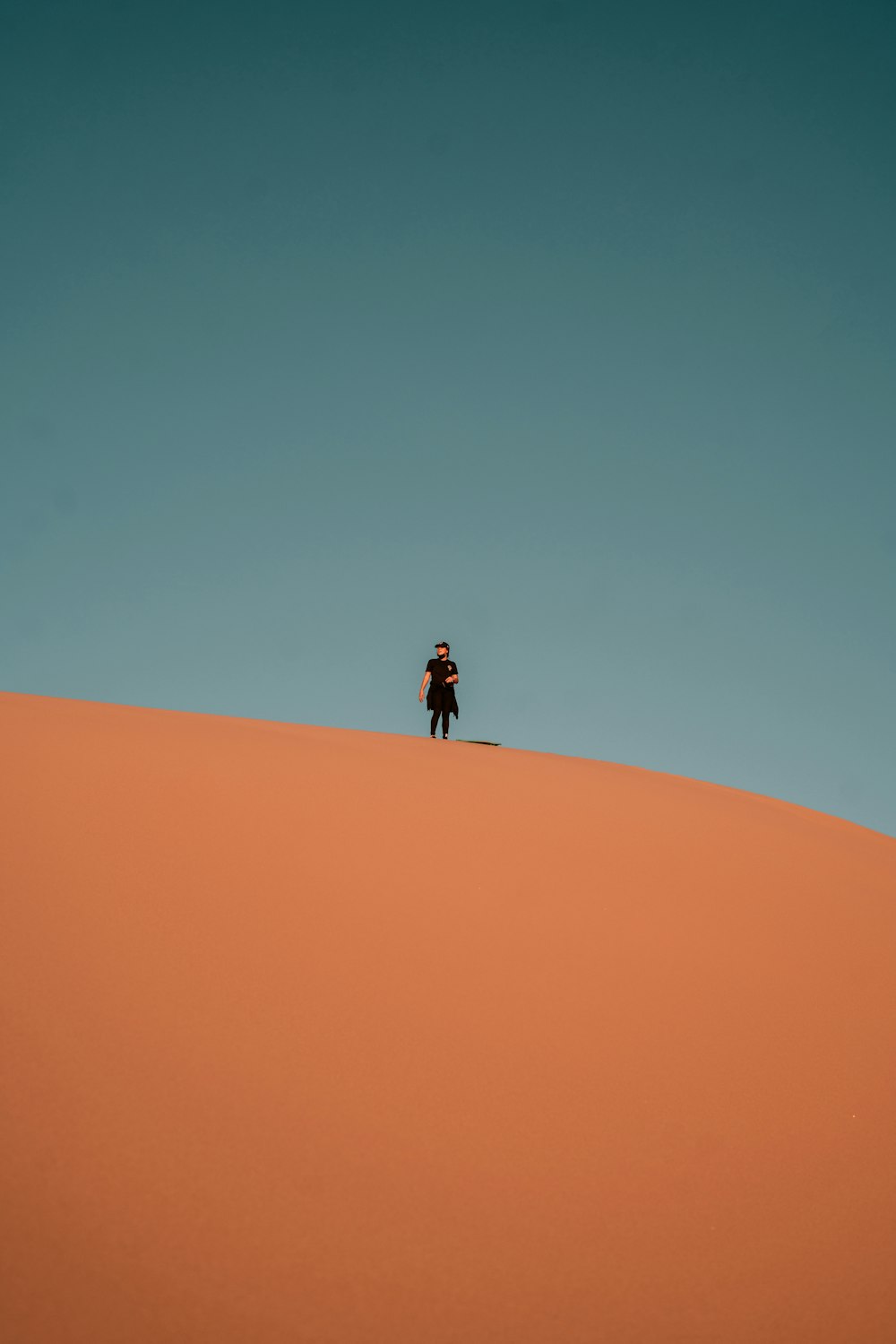 person in black jacket walking on desert during daytime