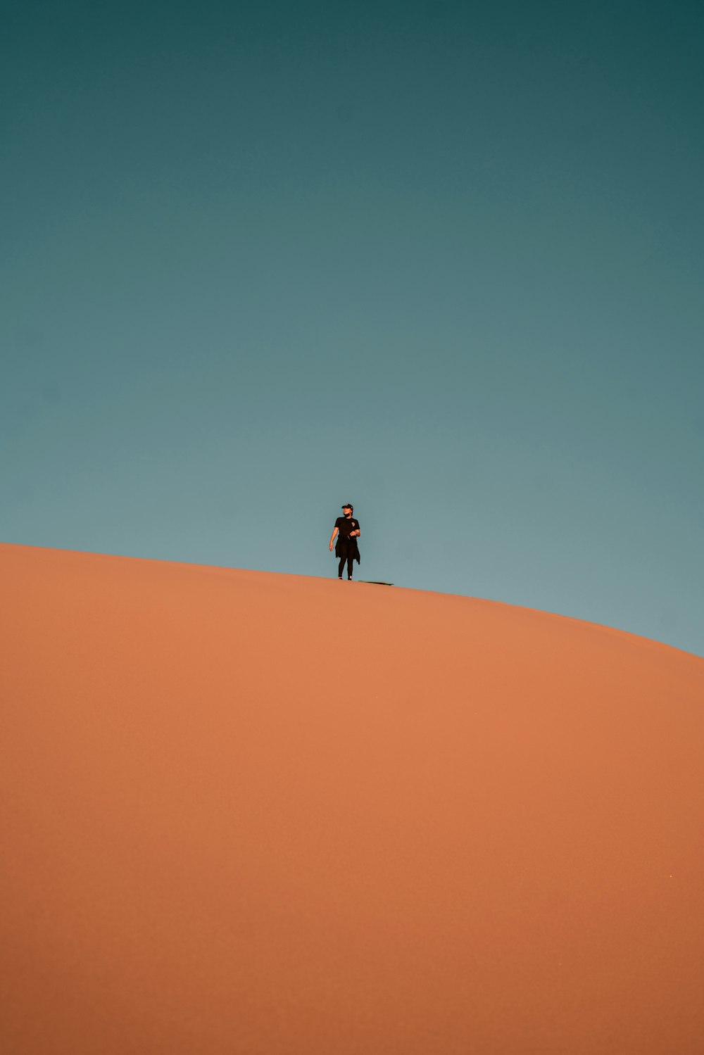 personne en veste noire marchant sur le désert pendant la journée